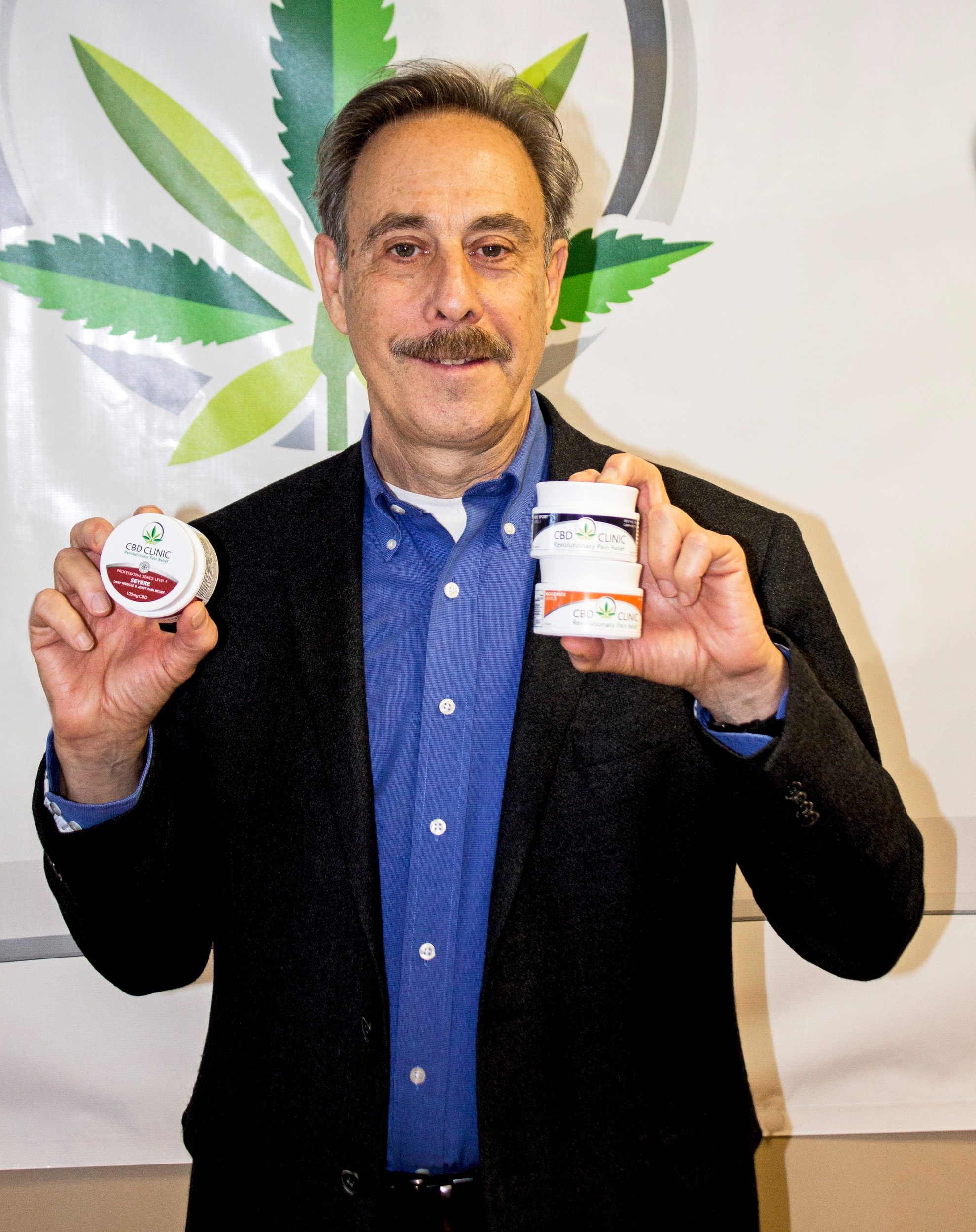 David Goldsmith, whose firm, CBD Clinic, has developed a new, non-prescription topical product to help relieve chronic pain, using CBD extract from marijuana, proudly displaying jars of his new product.