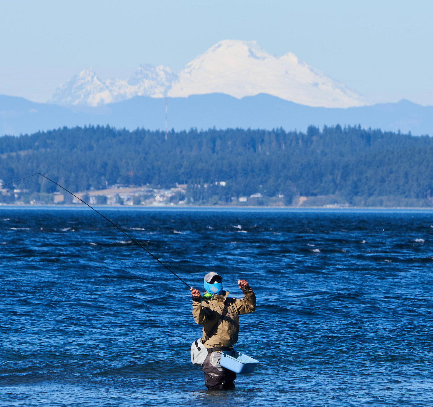 A fisherman in Hansville, Wash., with the Cascades in the distance, with the Mount Baker on the horizon.