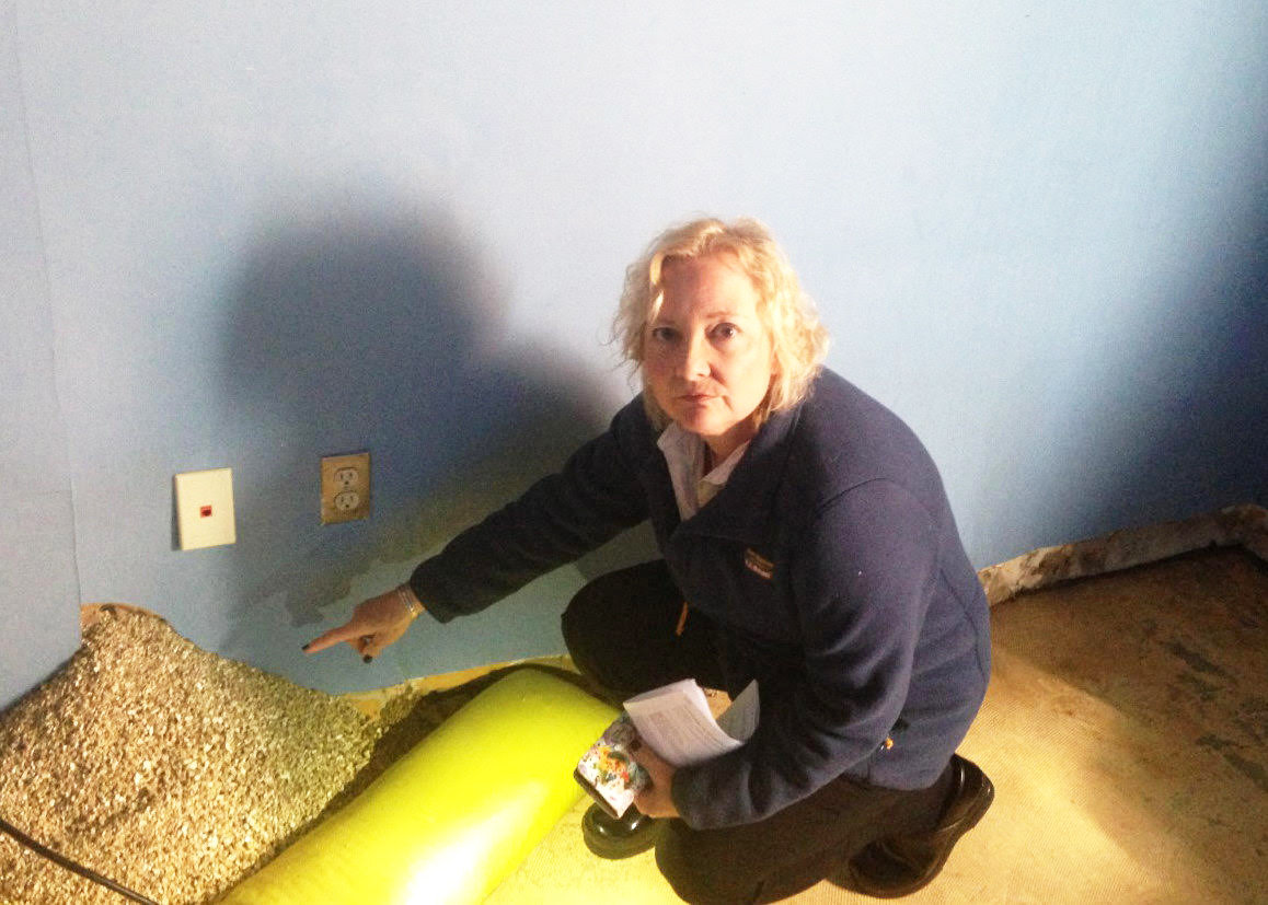 Karen Rathbun, vice president of administrative services at Community Care Alliance in Woonsocket, points to a hole in the wall with insulation pouring out, caused by water damage from a leak in the roof at the state-owned building. The leak had been identified in 2017 but was never repaired by the R.I. Department of Administration, leading to unhealthy conditions, including black mold, forcing the agency to move to temporary offices.